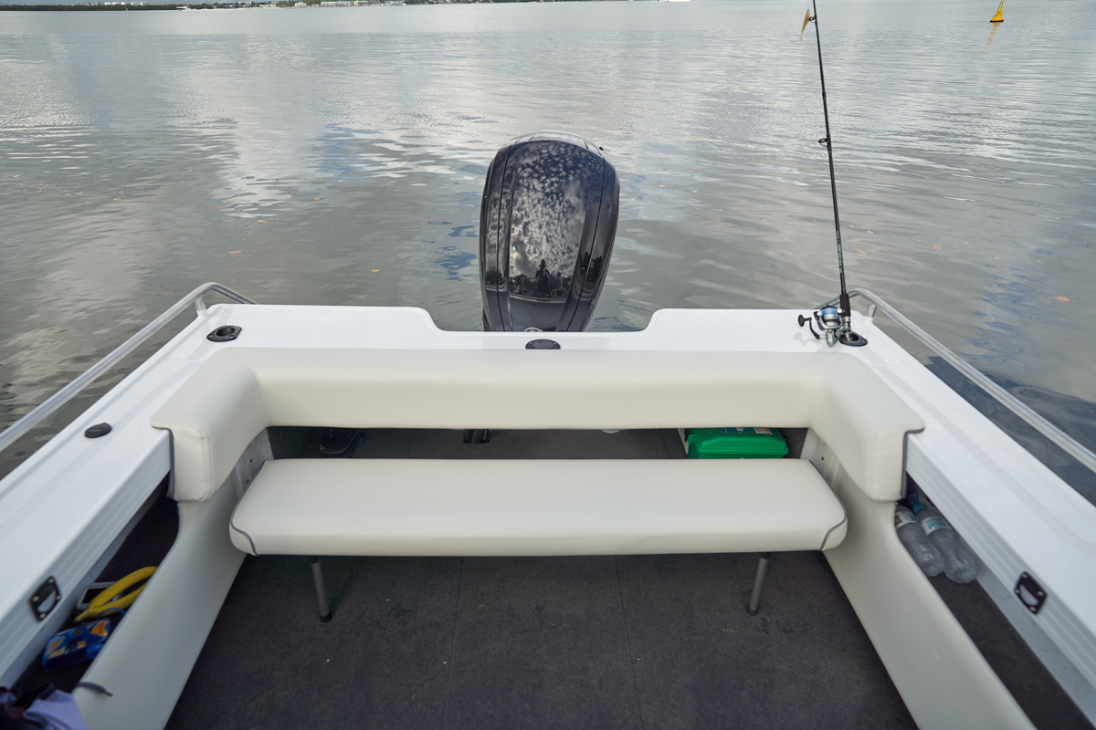Small white aluminum boat with a bench seat, storage compartments, outboard motor, and fishing rod holders